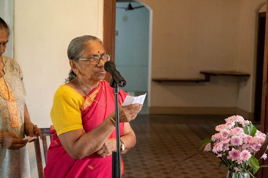 A person in a red and yellow dress holding a paper and a microphone

AI-generated content may be incorrect.
